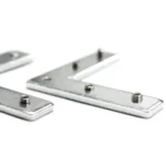 Two silver L-shaped metal brackets with small screws on a white surface
