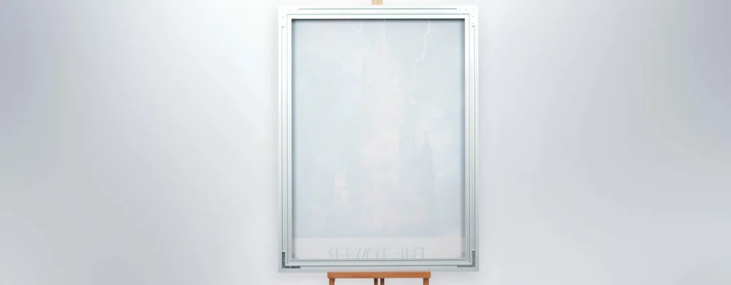 Tall vertical frosted glass panel in a metal frame mounted on a plain light wall, with a small wooden easel/stand at the bottom.