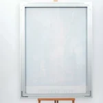 Tall vertical frosted glass panel in a metal frame mounted on a plain light wall, with a small wooden easel/stand at the bottom.