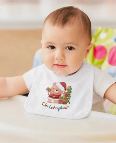 Smiling baby wearing a white Christmas bib with Santa and a tree, the name Christopher printed below