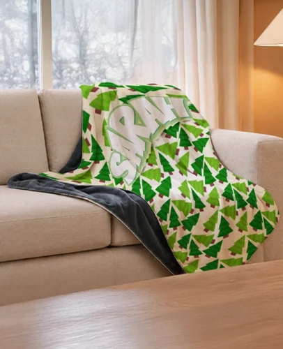 Beige sofa with a bright green geometric blanket draped over it, plus a dark throw on the seat and a warm lamp in the background.