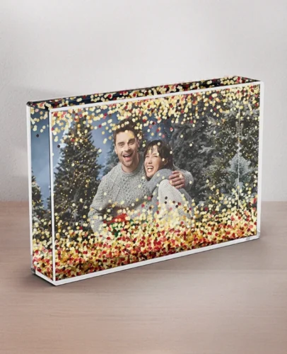 Decorative photo frame showing a couple embracing in a snowy scene, covered with colorful confetti sprinkled across the image edge-to-edge (festive aesthetic).